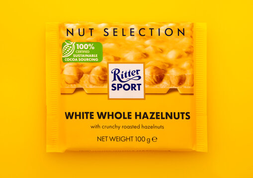 LONDON, UK - JANUARY 27, 2025: Ritter Sport chocolate bar with white whole hazelnuts on yellow background.