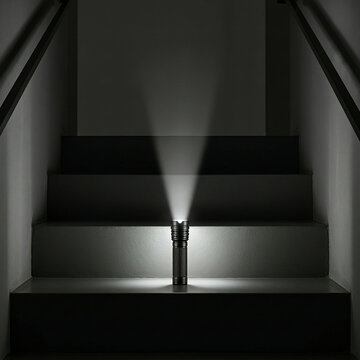 Bright LED flashlight beam illuminating dark indoor staircase at night