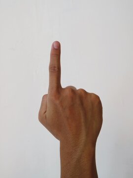 A human hand showing the index finger pointing upwards against a plain white background.
