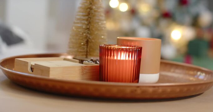 Camera shifting focus is making red ribbed candle flicker and glow on tray, capturing holiday glow
