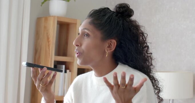 African American woman joining call, holding phone flat, speaking, gesturing to make point at home