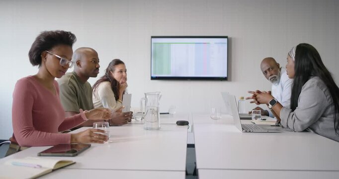 Diverse coworkers sitting at conference table, presenter starting discussion sharing spreadsheet
