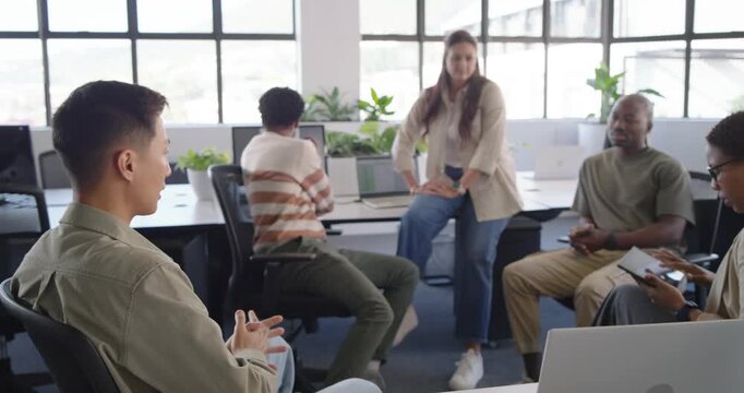 Man in striped sweater opening notebook and replying to colleague while team watching at office