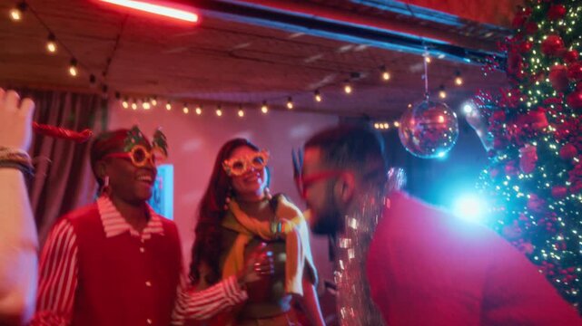 Diverse young friends dancing and celebrating Christmas with party blowers near holiday tree. Footage suitable for winter holiday campaigns and social event advertising