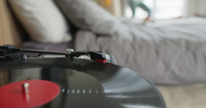 Tonearm is tracking inward across spinning vinyl after stylus contact, playing music in bedroom