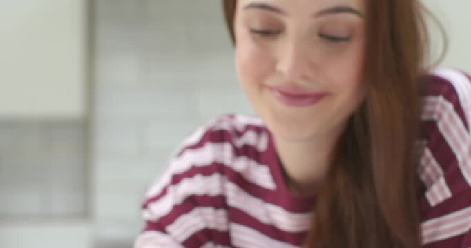 Woman holding purple phone by mug in kitchen, camera pulling back revealing her smiling at message