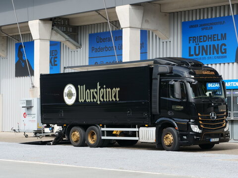 Germany, Paderborn, September 02. 2026, Black Mercedes-Benz Actros delivery truck with Warsteiner beer branding parked outside a football stadium