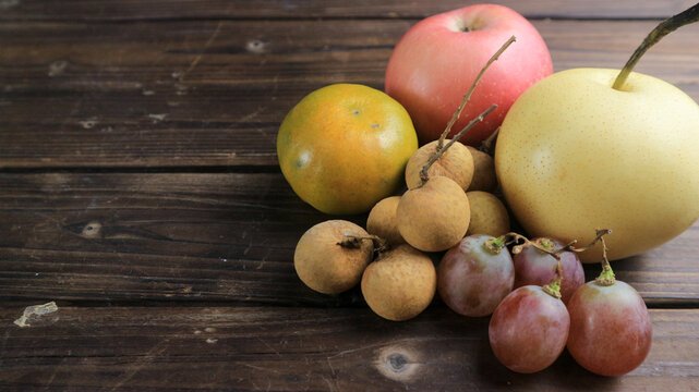 Assorted fresh fruits on dark wooden background with copy space. Healthy food and nutrition concept