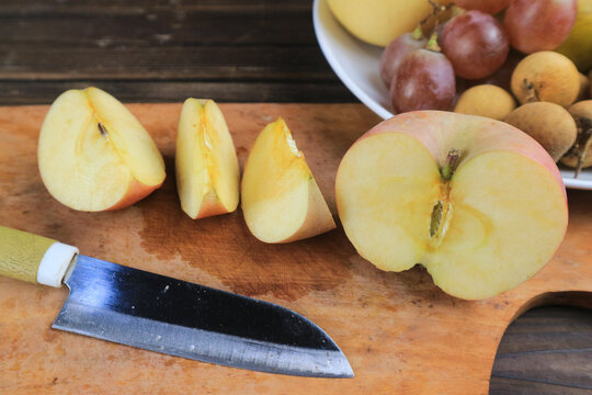 Sliced apple on cutting board with kitchen knife, rustic fruit still life background, copy space