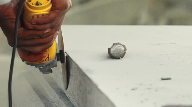 View of a worker using an angle grinder to shape and refine a modern sculpture in India.
