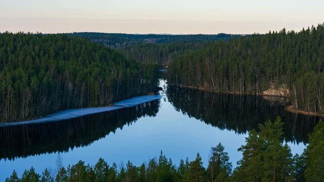 View of Repovesi National Park with dense coniferous forest surrounding the calm lake waters in Kouvola, Finland. Timelapse.