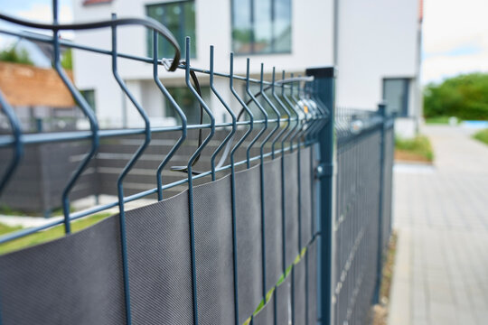 Metal mesh fence with privacy screen beside modern residential property