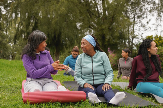 Happy multiracial women having fun together after yoga class - Multi generational people with different ethnic sitting outdoor at city park