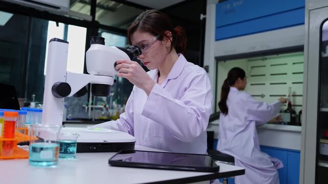 Woman researcher performing experiments in a contemporary lab utilizing advanced technology and microscopes