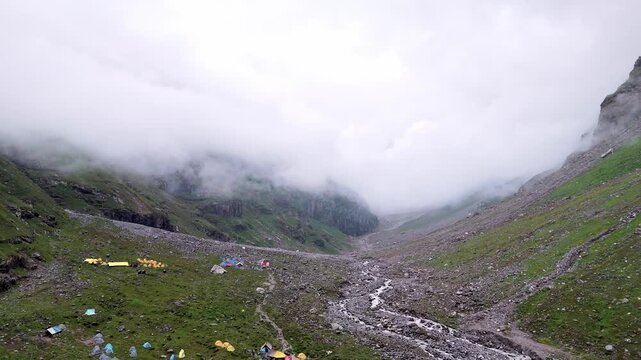 Aerial Drone View of Balu Ka Ghera on the Hampta Pass Trek Near Manali, Himachal Pradesh with Mountain Camping Tents, Small Flowing Streams, Rugged Himalayan Valleys and Cloud Covered Mountains