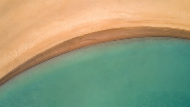 Aerial View of Curved Sandy Beach Shoreline along Emerald Green Ocean Water