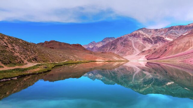 Aerial Drone View of Chandratal Lake in Spiti Valley, Himachal Pradesh with Crystal Blue Water, Rugged Himalayan Mountains and Bright Sunny Sky