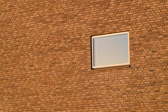 Modern rectangular window on textured orange brick wall with natural sunlight