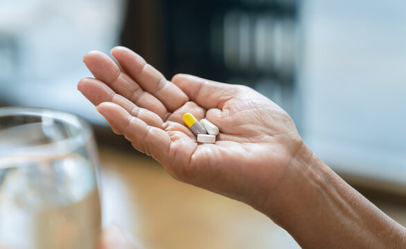Elderly Asian woman holding medicine in hand at home, medication and senior healthcare.