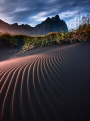 Fine wind-shaped ripples stretch across dark sand toward distant mountains, creating a dramatic minimalist landscape ideal for geology, travel, desert themes and abstract backgrounds. © UQink