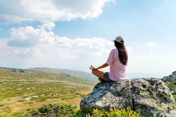 Relaxed woman meditating and  breathing fresh air in the summer mountain	
