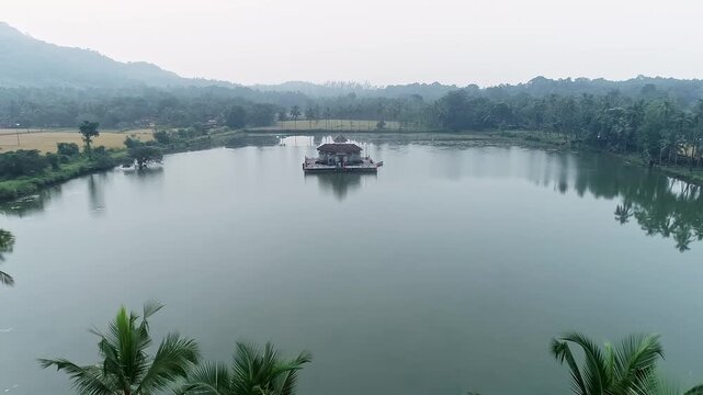 An aerial drone video of Kere Basadi temple floating peacefully within the picturesque Varanga Lake