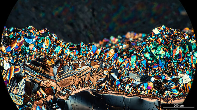 Abstract microscopic landscape of vibrant iridescent crystals under polarized light