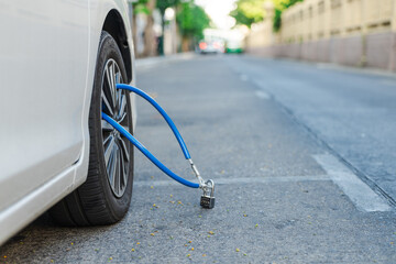 White Car Wheel Secured with Blue Cable and Padlock on Bangkok Street