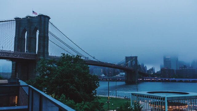 View of the iconic Brooklyn Bridge shrouded in fog over the East River with the city skyline in the background, New York, New York, United States.