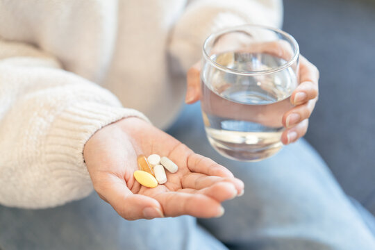 Close-up hands of person holding painkiller pills and water