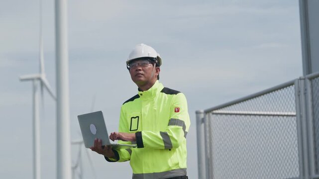 Engineer Using Laptop Wind Farm Near Wind Turbine, Renewable Energy Maintenance Technology, Safety Helmet, High Visibility Jacket, Outdoor Engineering Work Supporting Clean Power Infrastructure