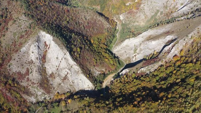  Aerial top down view of deep canyon, gorge road in autumn forest 