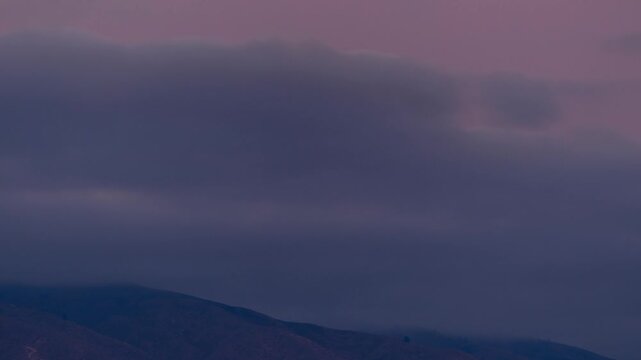 View of rolling mountains under a dramatic cloudy sky at dusk in Boise, Idaho, United States.