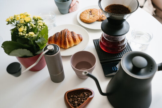 Coffee morning at home. Home Pour Over Coffee Brewing with V60 Paper Filter, Fresh Ground Coffee, Glass Server on Digital Scale, Hand Grinder, Gooseneck Kettle, Coffee Beans, Croissant, Cookies and Fl