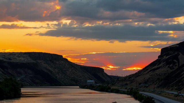 View of the vibrant sunset over Lucky Peak Lake with dramatic clouds and rocky hills in Ada County, Idaho, United States.