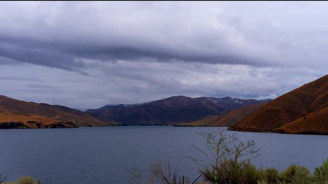 View of Lucky Peak Lake surrounded by rolling mountains under a cloudy sky in Ada County, Idaho, United States.