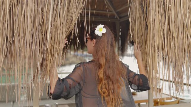Rear View of Woman Entering a Thatched Oceanfront Cabana