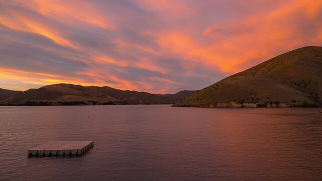 View of a serene lake at sunset with rolling hills and a floating platform in Idaho, United States.
