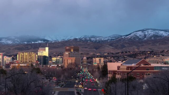 View of the Boise city skyline at sunset with golden light illuminating the buildings and the snow-capped foothills in the background in Boise, Idaho, United States.