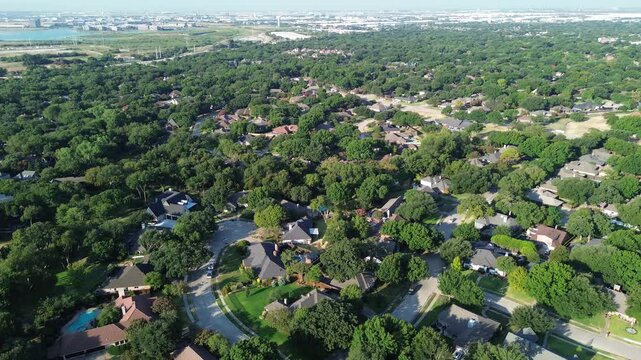 Faraway lake waters glint past tree covered neighborhood blocks within prominent Dallas suburbs. Lush hardwood groves shelter private homesteads across peaceful Coppell, Texas