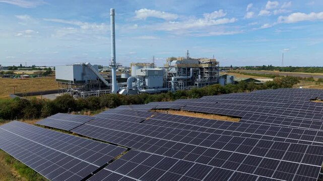 Aerial view of biomass energy recovery power plant and solar panel array in rural UK