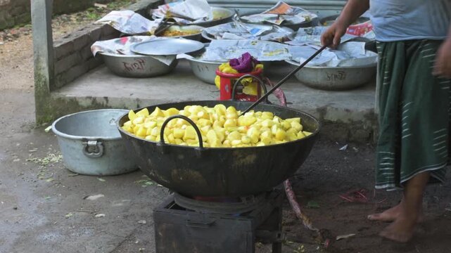 Indian Man Cooking Chopped Potatoes in a Large Wok