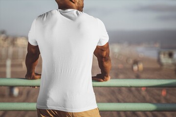 Obraz premium Man in white t-shirt looking over beach promenade