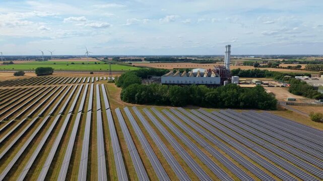 Aerial panning shot contrasting modern green solar farm with gas turbine power station Sutton Bridge UK