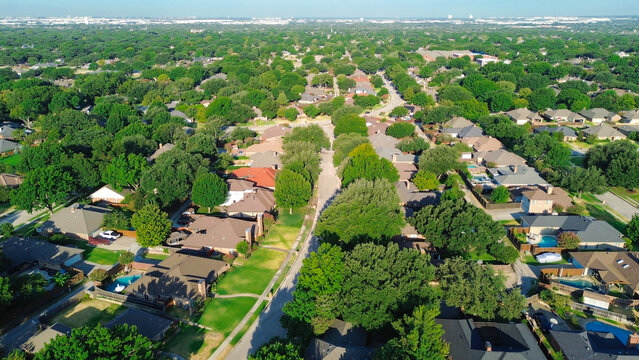 Curved residential concrete streets flank Mockingbird Lane across verdant North Texas subdivisions. Vibrant private yards encircle single family dwellings across Coppell, Texas