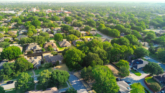 Towering hardwood canopies shelter curved residential roadways throughout Northwest Dallas County. Shingled rooftops intersperse dense mature foliage across Coppell, Texas
