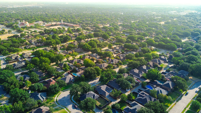 Sprawling tree cover shelters winding neighborhood avenues within classic DFW Metroplex zones. Sunny lawns surround single family residences across quiet neighborhoods in Coppell, Texas