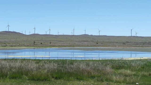 Scenic landscape of salt lake wetland and distant wind turbines in summer in Ulan Hada Volcano Geopark, Ulanqab, Inner Mongolia, China
