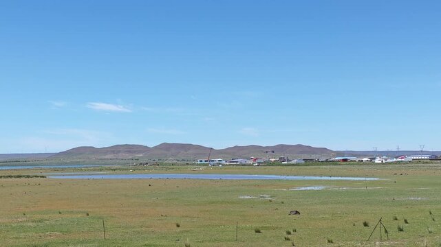 Scenic landscape of salt lake wetland and distant wind turbines in summer in Ulan Hada Volcano Geopark, Ulanqab, Inner Mongolia, China