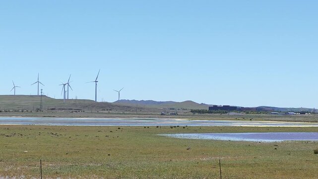 Scenic landscape of salt lake wetland and distant wind turbines in summer in Ulan Hada Volcano Geopark, Ulanqab, Inner Mongolia, China